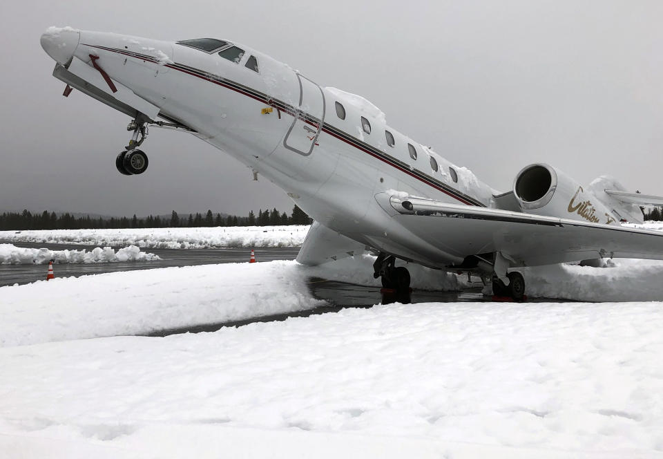 This Wed. Jan. 16, 2019 photo shows an overnight accumulation of about 20 inches of heavy wet snow dubbed "Sierra cement" causing a Cessna Citation X business jet at an outdoor parking spot to do a tail stand at Truckee Tahoe Airport in Truckee, Calif. Airport official Marc Lamb photographed the aircraft before mechanics cleared the snow. No injuries were reported. (Marc Lamb via AP)