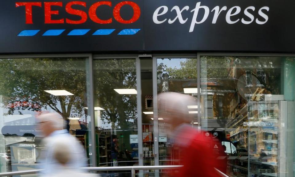 Pedestrians pass a Tesco shop