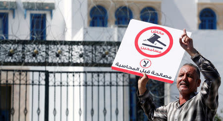 A demonstrator shout slogans during a demonstration against a bill that would protect those accused of corruption from prosecution in front of Assembly of the Representatives of the People headquarters in Tunis, Tunisia September 13, 2017. The sign reads: "No. We will not forgive." REUTERS/Zoubeir Souissi