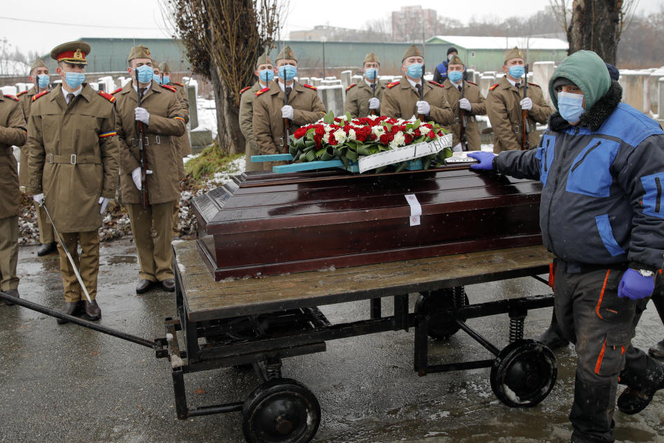 FILE - In this Jan, 11, 2021 file photo, the coffin of Iancu Tucarman is is transported on a cart, past an honor guard, at a Jewish cemetery for burial after dying of COVID-19 in Bucharest, Romania, Monday, Jan. 11, 2021. After the European Union passed the death toll of half a million citizens lost to the coronavirus on Wednesday, Feb. 10, 2021, the EU Commission chief said that stalling rollout of the vaccines could be partly blamed on the bloc being over-optimistic, over-confident and plainly "too late." (AP Photo/Vadim Ghirda, File)