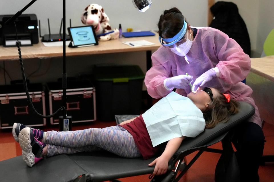 Dental hygienist Mary Davis examines Amber Warner's teeth at the Christa McAuliffe School in Concord, N.H., Wednesday, Feb. 21, 2024. Mobile clinics provide critical dental access as do state programs that focus on preventive care and ensure dental care is incorporated into overall health efforts. (AP Photo/Robert F. Bukaty)