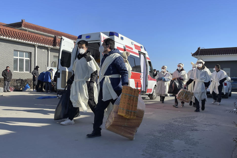 Relatives carry paper offerings to burn for their dead relative at the Gaobeidian Funeral Home in northern China's Hebei province, Thursday, Dec. 22, 2022. Bodies from Beijing, a two-hour drive away, are appearing at the Gaobeidian funeral home, because similar funeral homes in Beijing were packed. (AP Photo)