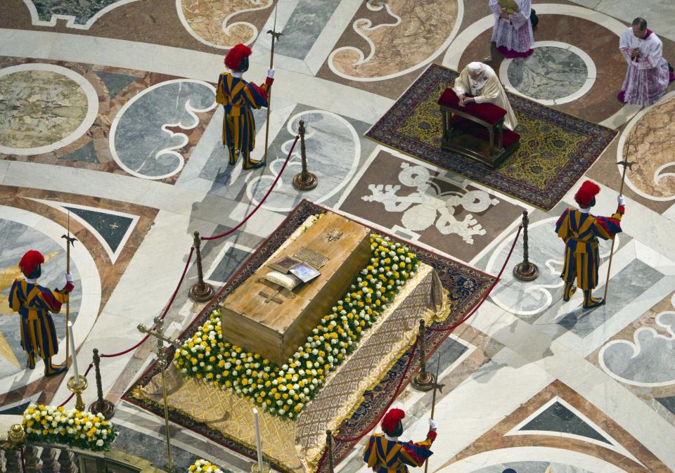 FILE - Pope Benedict XVI, top right, kneels in prayer in front of the casket of late Pope John Paul II, laid out in state at the Altar of the Confession inside St. Peter's Basilica, at the end of a solemn celebration in St. Peter's Square where John Paul II was beatified on May 1, 2011. Pope Emeritus Benedict XVI, the German theologian who will be remembered as the first pope in 600 years to resign, has died, the Vatican announced Saturday. He was 95. (AP Photo/Andrew Medichini, Pool, file)