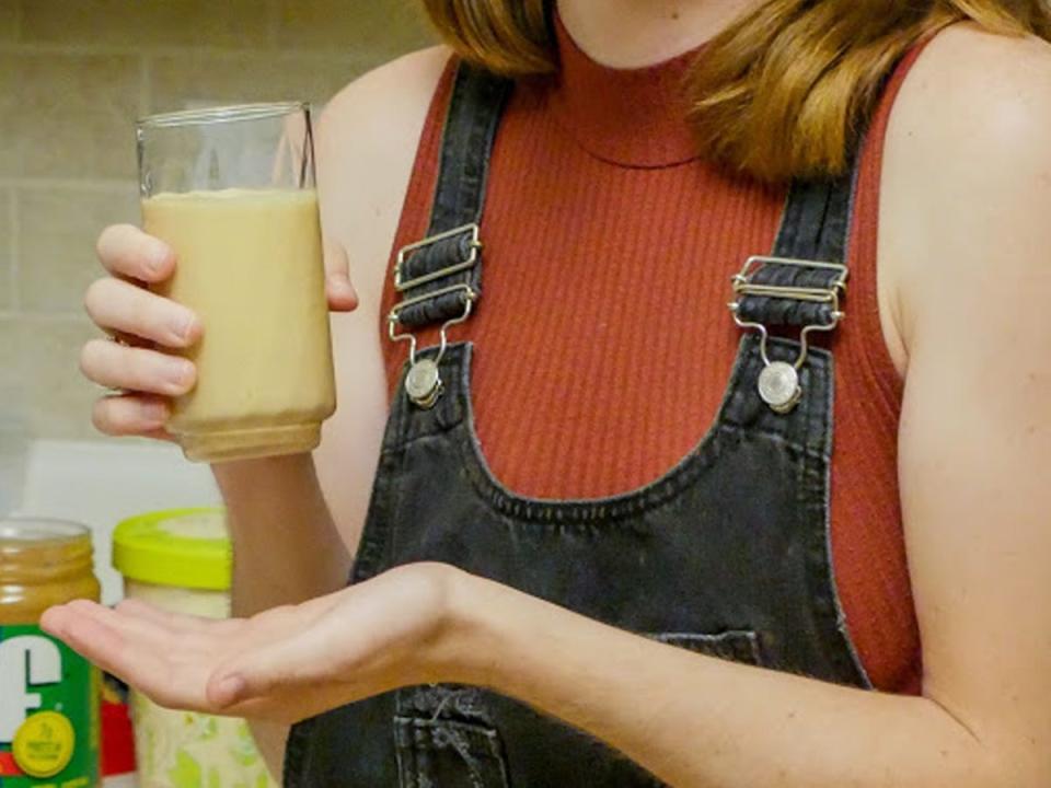 The writer holding the completed Survivor smoothie in a glass cup