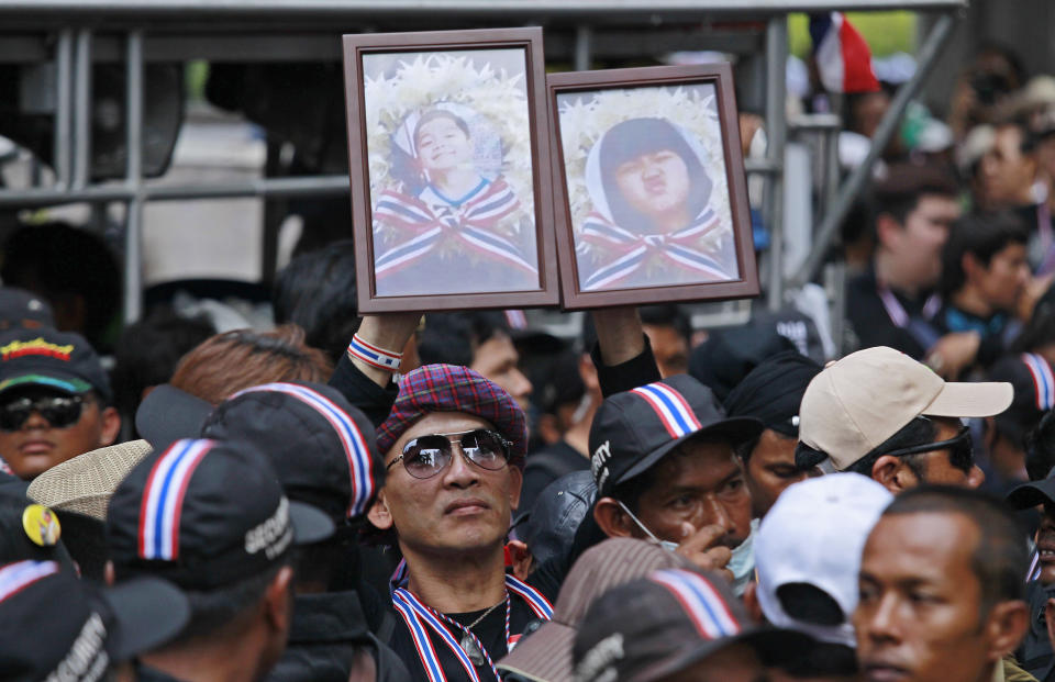 Anti-government supporters hold portraits of children killed in recent blast attacks during a memorial outside the police headquarters in Bangkok, Thailand, Wednesday, Feb. 26, 2014. Violence spread Tuesday to another anti-government protest site in Thailand's capital following weekend explosions that left five people dead, including four children, security officials said. (AP Photo/Wally Santana)