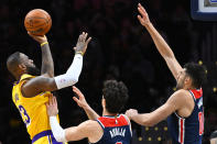 Los Angeles Lakers forward LeBron James, left, scores over Washington Wizards forward Deni Avdija and forward Tristan Vukcevic, right, during the first half of an NBA basketball game Wednesday, April 3, 2024, in Washington. (AP Photo/John McDonnell)