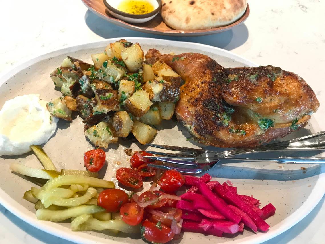 The roast chicken entree at Meddys comes with garlicky potatoes, tomato-onion relish, pickles and pita.
