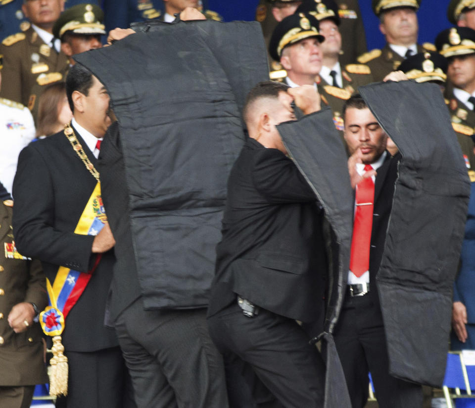 In this photo released by China's Xinhua News Agency, security personnel surround Venezuela's President Nicolas Maduro, at left, during an incident as he was giving a speech in Caracas, Venezuela, Saturday, Aug. 4, 2018. Drones armed with explosives detonated near Venezuelan President Nicolas Maduro as he gave a speech to hundreds of soldiers in Caracas on Saturday but the socialist leader was unharmed, according to the government. (Xinhua via AP)