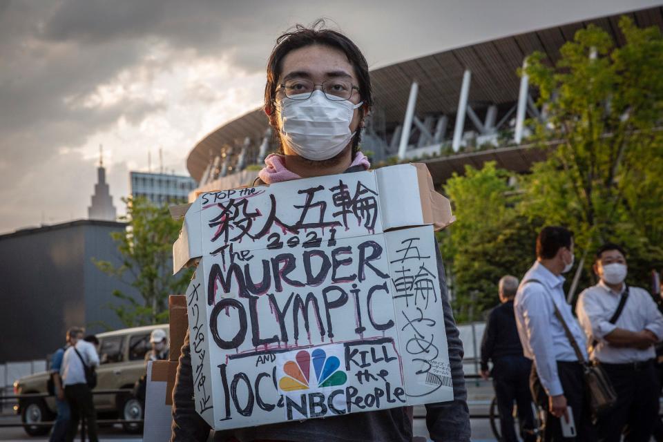 A masked protester holds a sign that reads 'stop the 2021 murder olympic' in Tokyo, Japan.