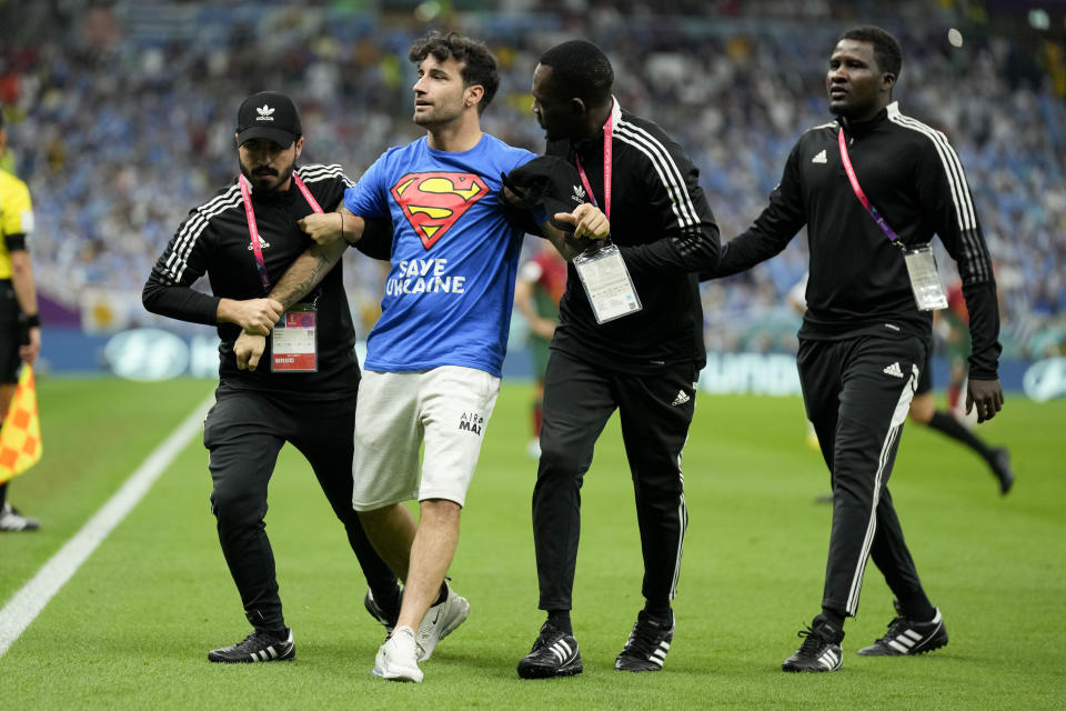 Un aficionado es detenido tras irrumpir en la cancha con la bandera arcoíris durante el partido del Grupo H entre Portugal y Uruguay, el lunes 28 de noviembre de 2022, en Lusail, Qatar. (AP Foto/Aijaz Rahi)