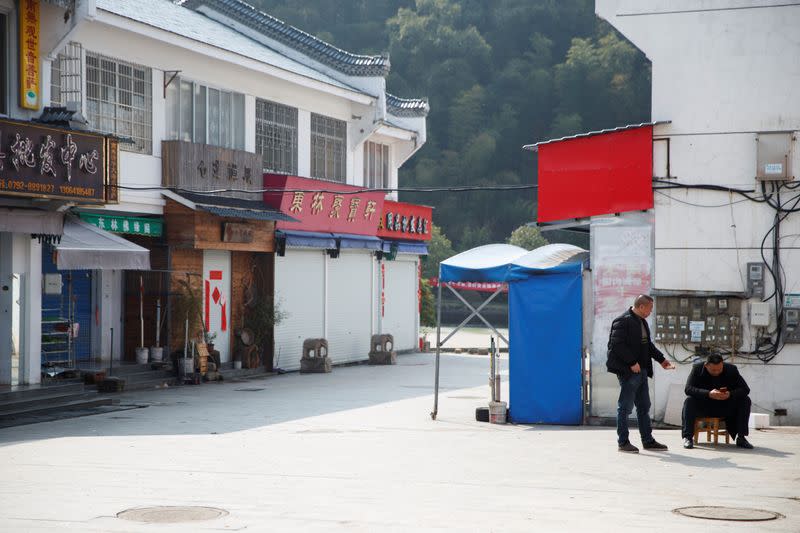 Men sit in a deserted restaurant street that normally caters for tourists in a village outside Donglin Temple that is under lockdown because of the coronavirus outbreak in Jiujiang