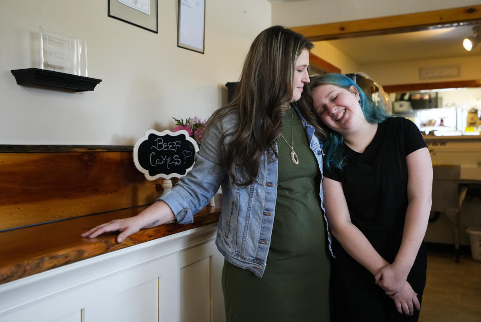 Khloe Warne, 12, stands for a photo with her mother, Alyssa, at the family bakery Beef Cakes, Thursday, May 18, 2023, in Grants Pass, Ore. Khloe was put on shortened school days by her school district after incidents in which she fought with students and threw a desk in outbursts her mother, Alyssa, attributes to a failure to support her needs. Now she only attends school one day a week for two hours, and hasn't been on a regular school schedule for years, instead spending much of her time at her mother's bakery or at the local library. (AP Photo/Lindsey Wasson)