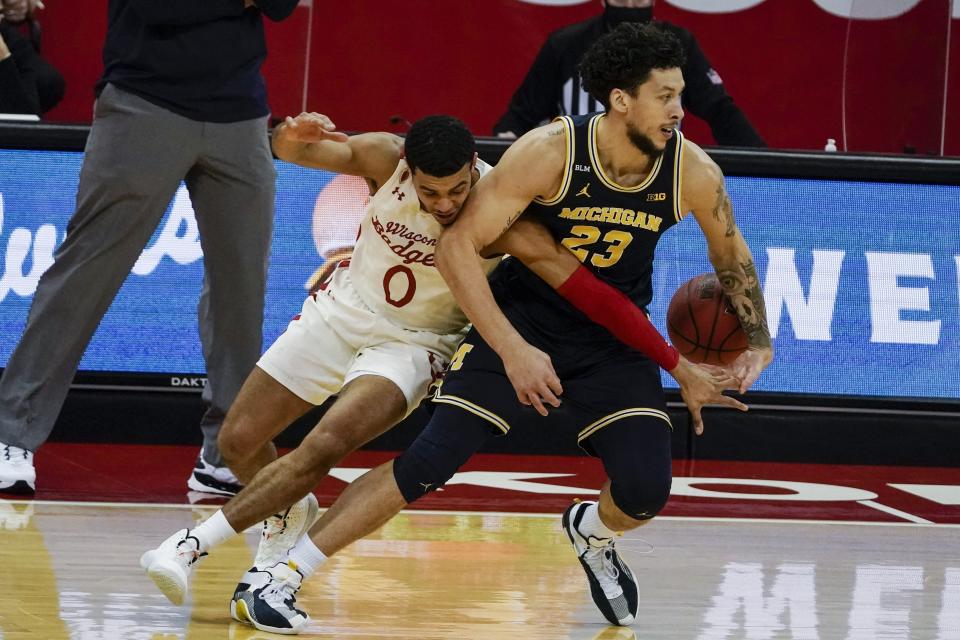 Wisconsin's D'Mitrik Trice tries to stop Michigan's Brandon Johns Jr. during the first half of an NCAA college basketball game Sunday, Feb. 14, 2021, in Madison, Wis. (AP Photo/Morry Gash)