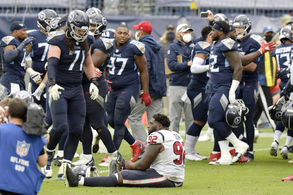 Houston Texans nose tackle Brandon Dunn (92) sits on the field as Tennessee Titans players celebrate after the Titans won 42-36 in overtime at an NFL football game Sunday, Oct. 18, 2020, in Nashville, Tenn. (AP Photo/Mark Zaleski)