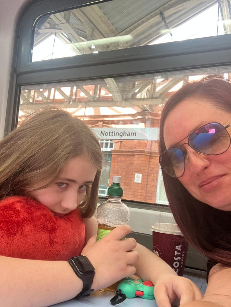 A mother and daughter take a selfie sat on a train with a Nottingham sign in the background