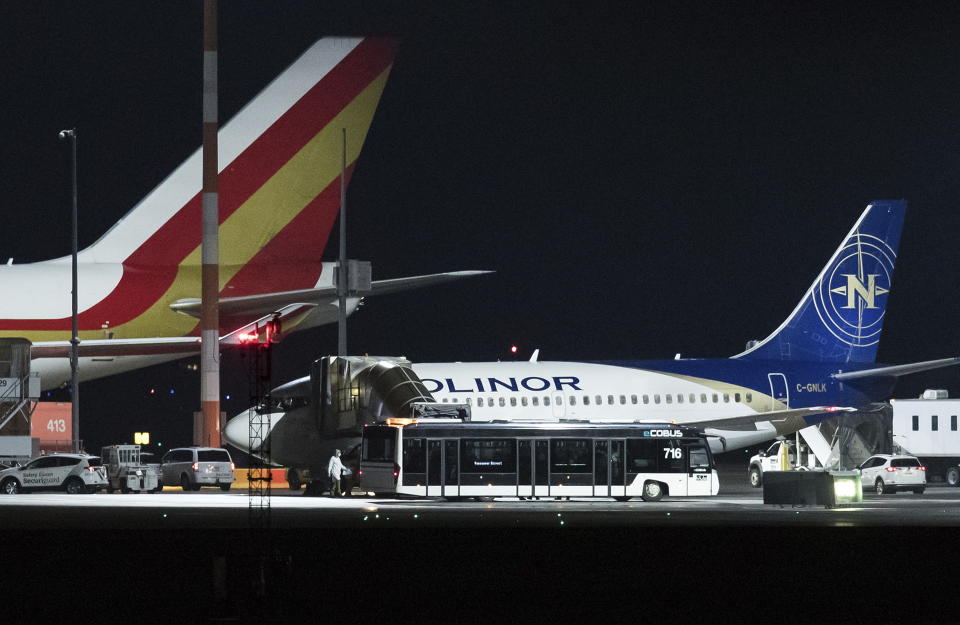 A person in protective clothing is seen as passengers board a charter flight bound for CFB Trenton after arriving on a plane chartered by the United States government carrying U.S. and Canadian citizens home from Wuhan, China, at Vancouver International Airport in Richmond, B.C., on Friday, Feb. 7, 2020. Canadians deplaned from the U.S. charter and the aircraft refueled before continuing on to a U.S. Air Force Base. (Darryl Dyck/The Canadian Press via AP)