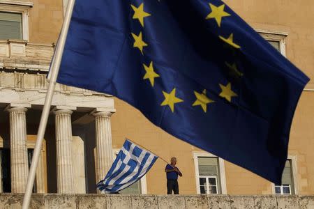 A protester waves a Greek flag at the entrance of the parliament building during a rally calling on the government to clinch a deal with its international creditors and secure Greece's future in the Eurozone, in Athens, Greece, June 22, 2015. REUTERS/Yannis Behrakis