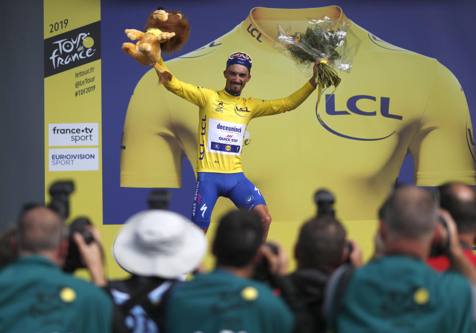 France's Julian Alaphilippe wearing the overall leader's yellow jersey celebrates on the podium after winning during the third stage of the Tour de France cycling race over 215 kilometers (133,6 miles) with start in Binche and finish in Epernay, Monday, July 8, 2019. (AP Photo/Thibault Camus)