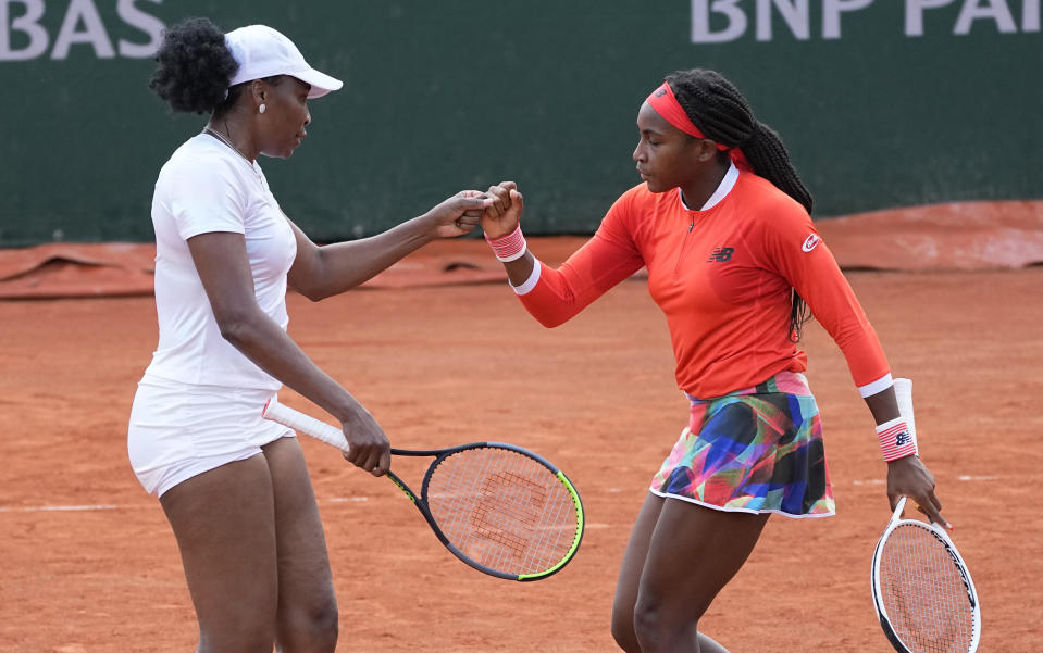 Venus Williams, left with doubles partner Coco Gauff of the United States bump fistsnafter winning a point against EllenPerez of Australia and Saisai Zheng of China in a first round women's doubles match day four of the French Open tennis tournament at Roland Garros in Paris, France, Wednesday, June 2, 2021. (AP Photo/Michel Euler)