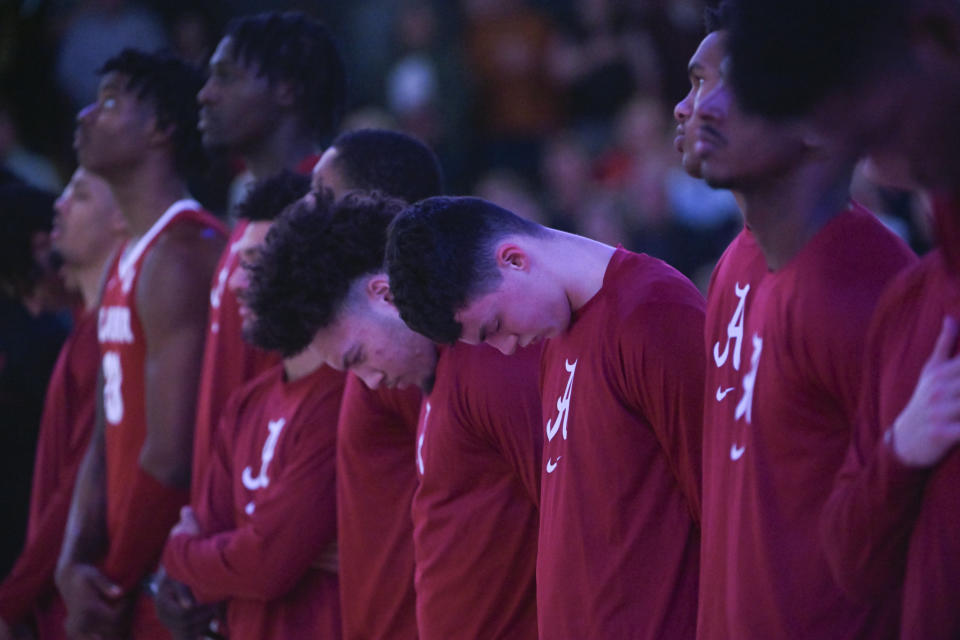 FILE - Under dim lights with the national anthem playing, Alabama players stand on the court before an NCAA college basketball game against Vanderbilt on Jan. 17, 2023, in Nashville, Tenn. At Alabama, one of the team's best players is connected to a killing for allegedly delivering a gun to a murder suspect. An Associated Press analysis of more than a dozen schools in the NCAA tournaments shows a wide range of policies that govern guns at those schools and uneven efforts to regulate them. (AP Photo/John Amis, File)