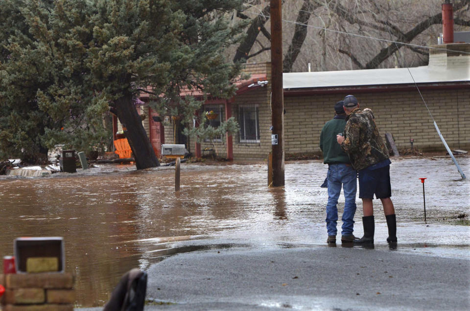 Residents look out on properties that flooded when a local creek overflowed in Lake Montezuma, Ariz., Tuesday, March 21, 2023. Evacuations were in effect in parts of north-central Arizona on Wednesday due to flooding. (Vyto Starinskas/The Daily Courier via AP)