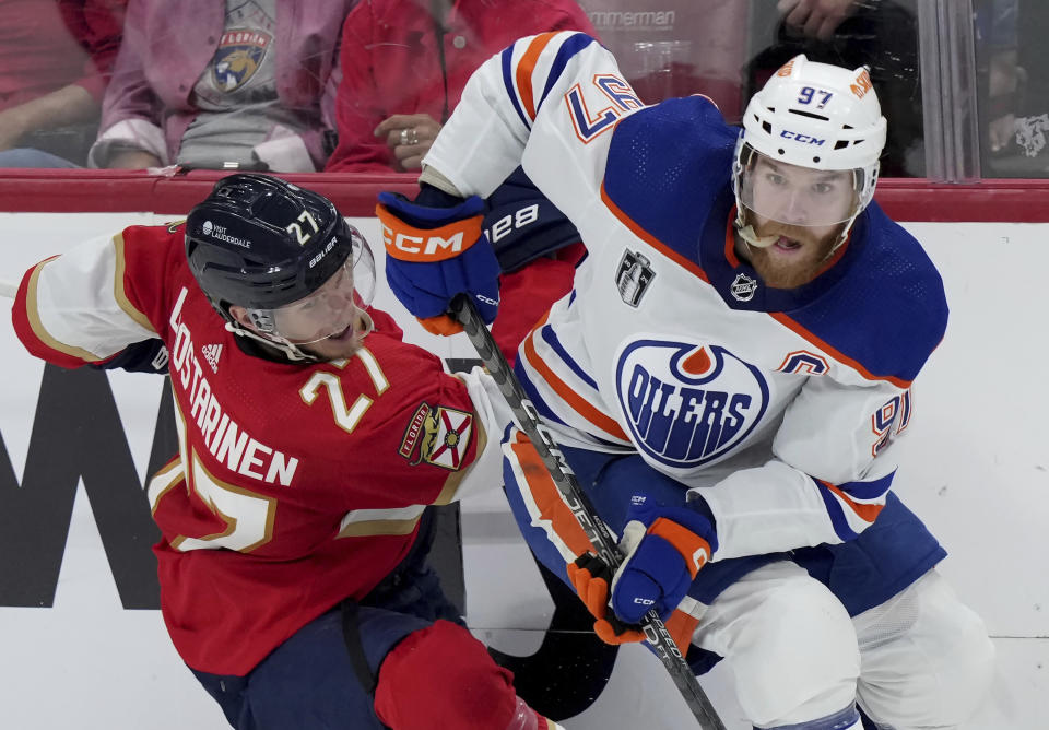 Edmonton Oilers forward Connor McDavid (97) dumps Florida Panthers forward Eetu Luostarinen (27) against the boards as he turns with the puck during the second period of Game 7 of the NHL hockey Stanley Cup Final in Sunrise, Fla., Monday, June 24, 2024. (Nathan Denette/The Canadian Press via AP)