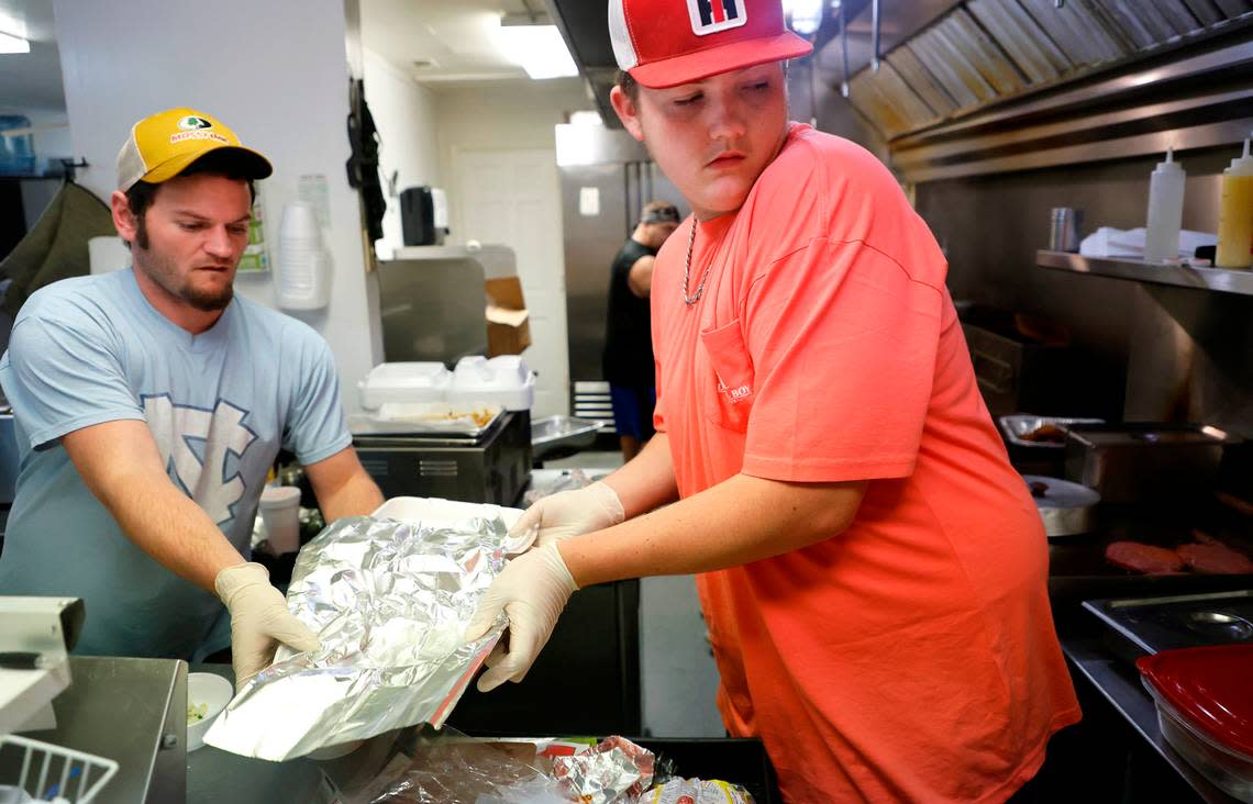 Tyler Hardy, left, and Peyton Jordan work on preparing an order during the lunch rush at Stubbs & Son BBQ in Carthage, N.C., Wednesday, Dec. 7, 2022. The restaurant got its power back Tuesday morning and has been extra busy as people look for meals and ‘people missed us’ said manager Gary Talley.