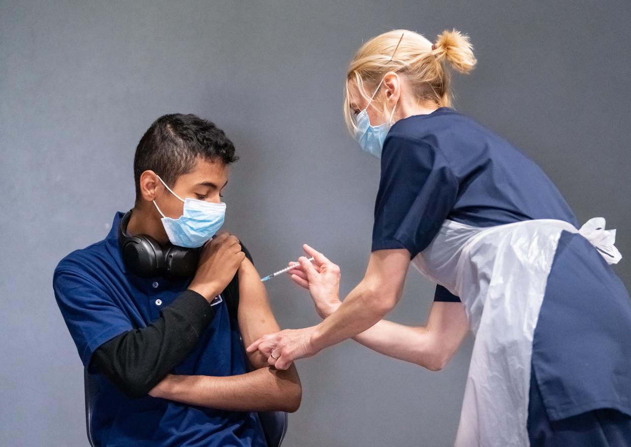 Nurse Sonia Wilson (right) vaccinates eighteen-year-old Cameron Ladd (left) with the Pfizer Covid-19 vaccine at a vaccination centre at Adwick Leisure Centre in Doncaster (Danny Lawson/PA) (PA Wire)