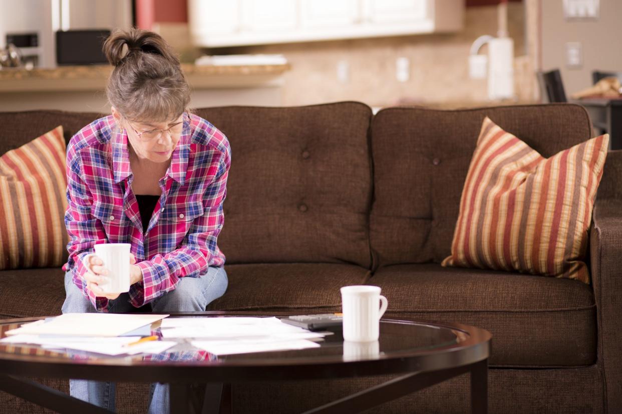 woman sitting on couch looking at bills