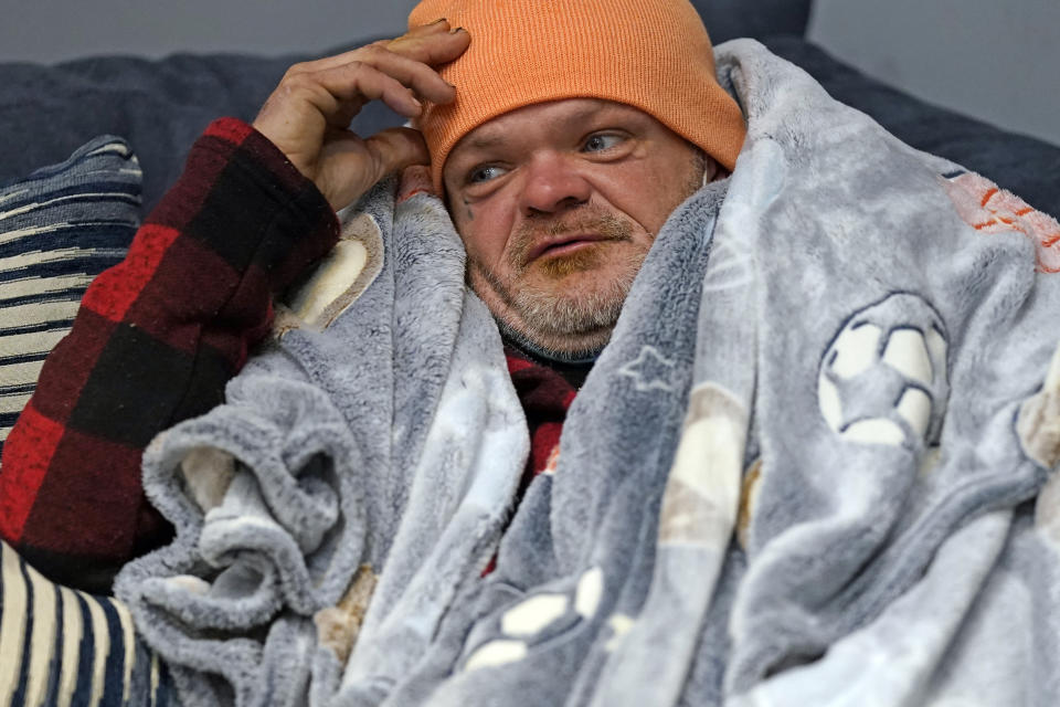 Brett Saint rests inside a Gallery Furniture store which opened as a shelter for those in need of food, water and heat Wednesday, Feb. 17, 2021, in Houston. Millions in Texas still had no power after a historic snowfall and single-digit temperatures created a surge of demand for electricity to warm up homes unaccustomed to such extreme lows, buckling the state's power grid and causing widespread blackouts. (AP Photo/David J. Phillip)