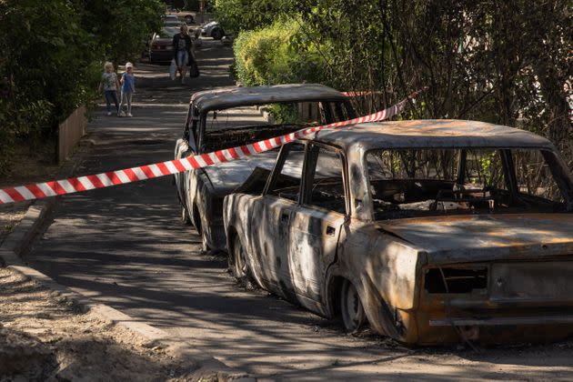 Дети смотрят на горящие автомобили на месте падения обломков перехваченного российского беспилотника, 31 мая 2023 года, Киев, Украина. 