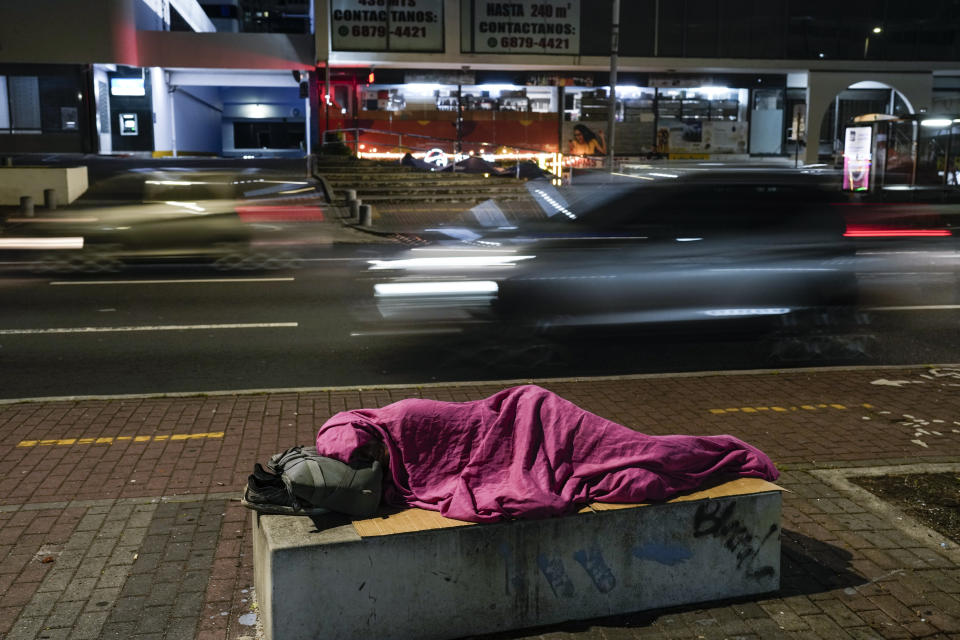 Una persona duerme en un banco de concreto junto a una calle en la Ciudad de Panamá, el viernes 26 de abril de 2024. (Foto AP/Matías Delacroix)
