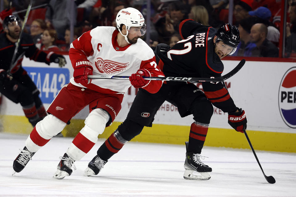 Carolina Hurricanes' Brett Pesce (22) clears the puck past Detroit Red Wings' Dylan Larkin (71) during the first period of an NHL hockey game in Raleigh, N.C., Friday, Jan. 19, 2024. (AP Photo/Karl B DeBlaker)