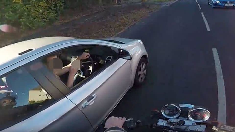 Strike two, the driver flipped off the motorcyclist who was trying to return his wallet. Source: YouTube