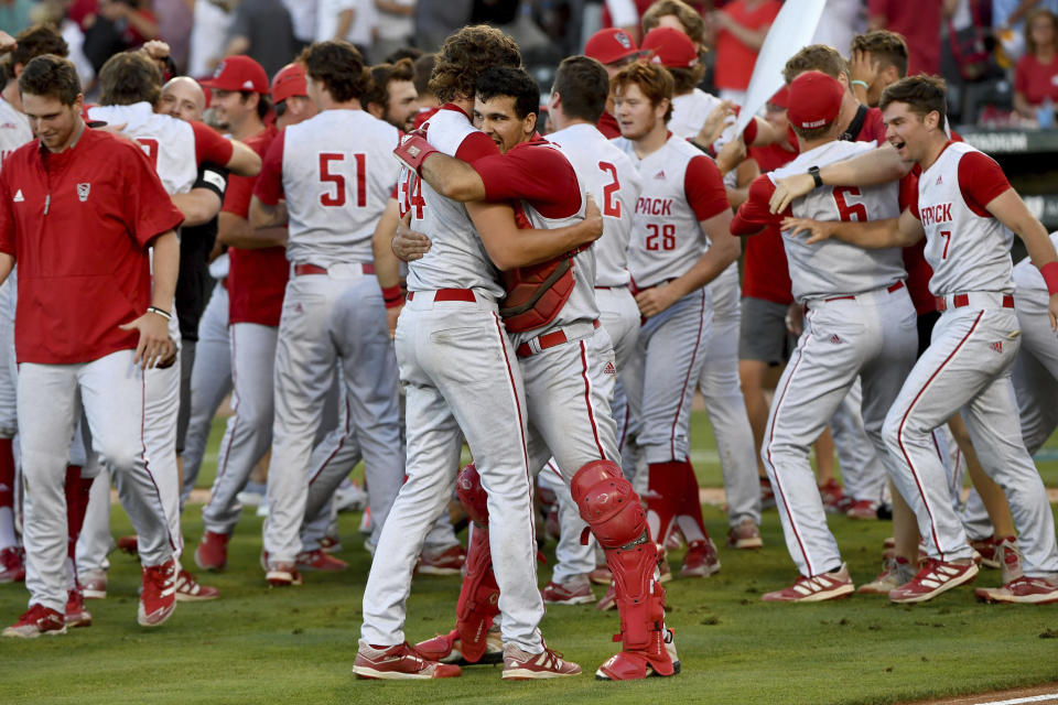 North Carolina State players Evan Justice (34) and Luca Tresh (24) hug following their 3-2 win over Arkansas during an NCAA college baseball super regional game Sunday, June 13, 2021, in Fayetteville, Ark. (AP Photo/Michael Woods)