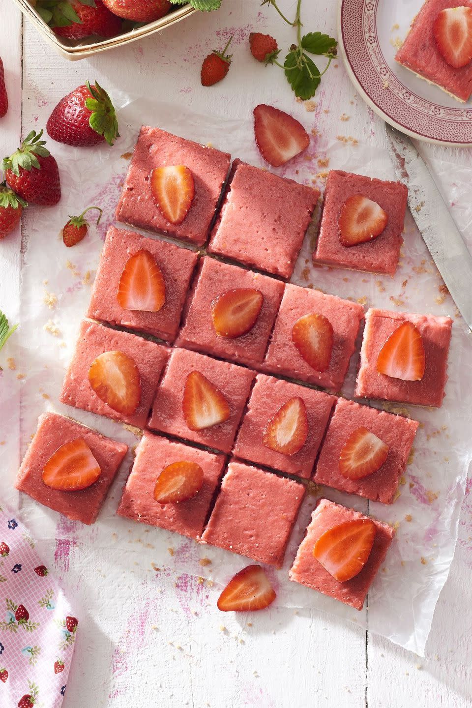 strawberry rhubarb shortbread bars cut into squares and topped with a slice of strawberry