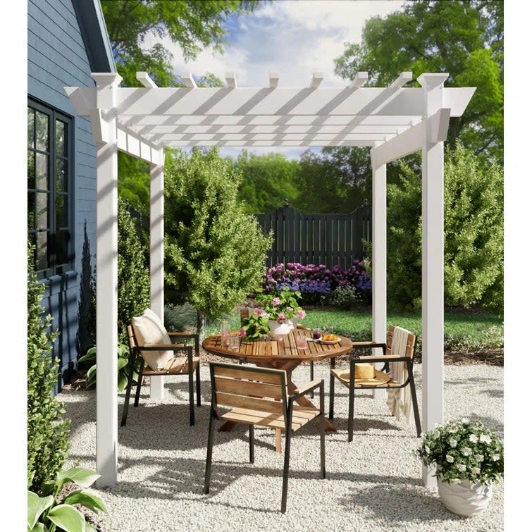 a white pergola over a backyard table set 