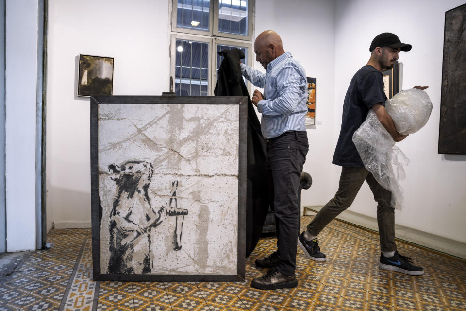 Koby Abergel, un marchante de arte israelí, devela una pintura del reservado grafitero británico Banksy que fue misteriosamente trasladada de la Cisjordania ocupada a la Urban Gallery en Tel Aviv, Israel, el jueves 4 de agosto de 2022. (Foto AP/Oded Balilty)