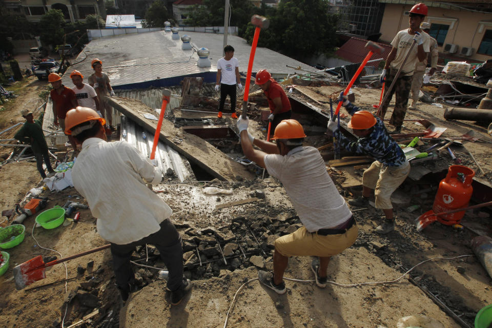 Rescuers try to remove the rubble at the site of a collapsed building in Preah Sihanouk province, Cambodia, Sunday, June 23, 2019. Rescue workers were using saws to cut steel beams and excavators to move piles of rubble of the collapsed seven-story building. (AP Photo/Heng Sinith)