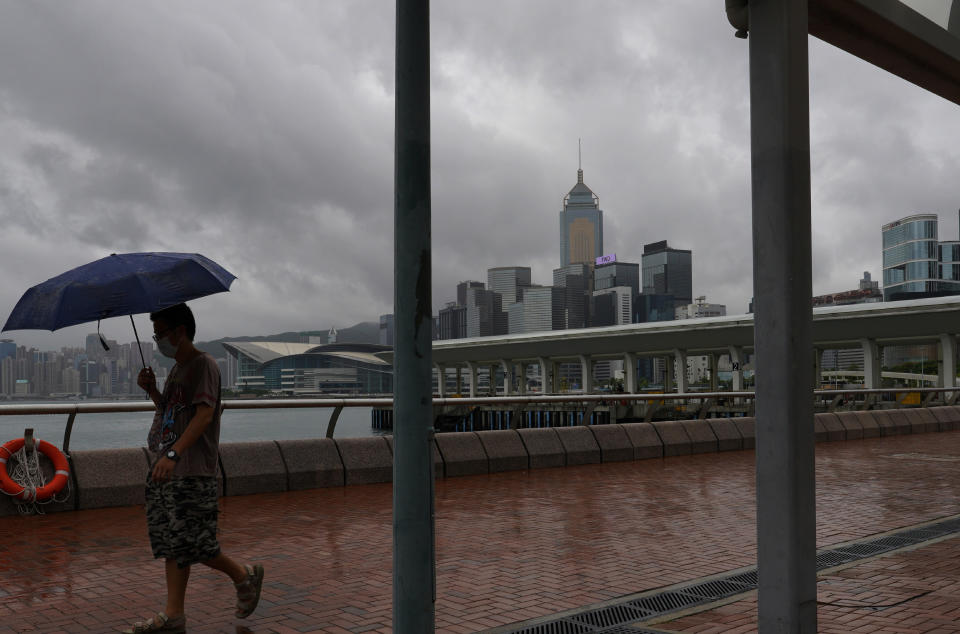 A man walks along the waterfront of Victoria Harbour in Hong Kong Wednesday, Aug. 19, 2020. Typhoon Higos weakened to a strong topical storm after making landfall in Zhuhai city on Wednesday morning on China's southern coast. (AP Photo/Vincent Yu)