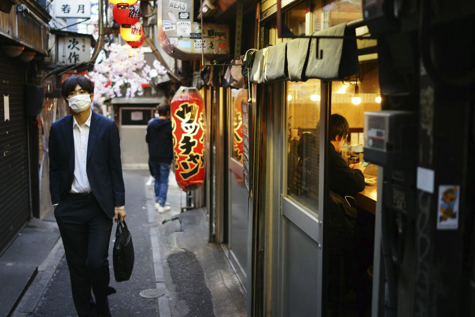 A man wearing a mask to help stop the spread of the new coronavirus walks along a bar alley in the Shinjuku Ward in Tokyo, Friday evening, April 24, 2020. Japan's Prime Minister Shinzo Abe expanded a state of emergency to all of Japan from just Tokyo and other urban areas as the virus continues to spread. (AP Photo/Eugene Hoshiko)