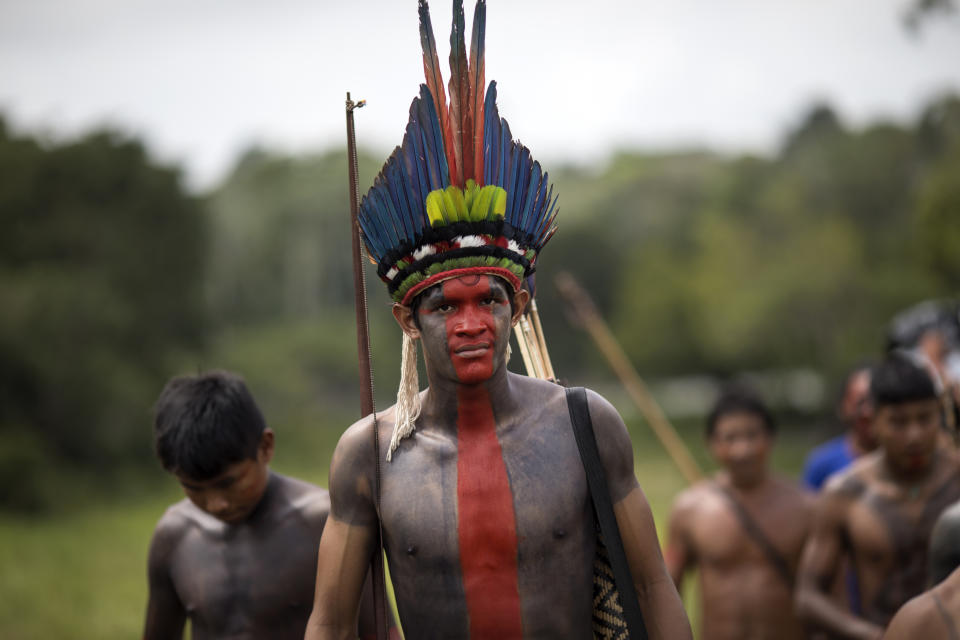 In this Sept. 3, 2019 photo, villagers arrive to a meeting of Tembé tribes in Tekohaw indigenous reserve, Para state, Brazil. Some of the men wore a type of red face paint that signified they were ready for war. Recent clashes saw the Tembe burning the trucks and equipment of illegal loggers on their territory, which is located in a Brazilian state plagued by thousands of fires burning on cleared jungle lands. (AP Photo/Rodrigo Abd)