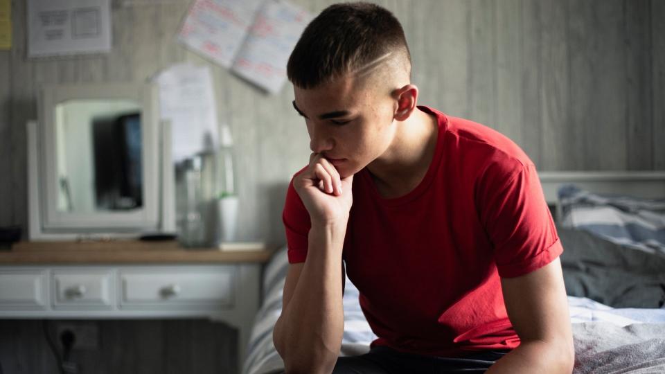 Emotional, low lighting shot of a teenage boy stressed about exams.