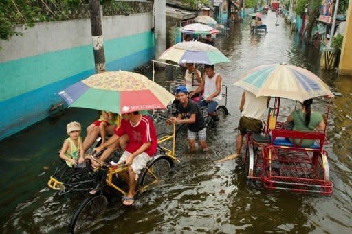 People use pedicabs to cross floodwaters in a street in Valenzuela, on the outskirts of Manila. The Philippine capital is braced for more wet weather and authorities rushed relief supplies to the remote northern Philippines as a new storm -- expected to trigger flashfloods and landslides -- closed in