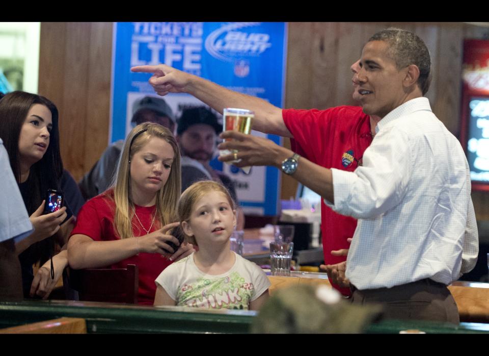 President Barack Obama holds a beer during a visit to Gator's Dockside restaurant in Orlando, Florida, on September 8, 2012 during the first day of a 2-day bus tour across Florida. AFP PHOTOS/SAUL LOEB