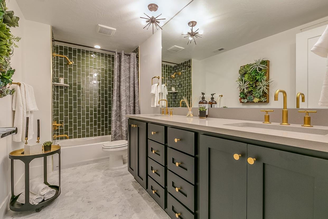 Trendy bathroom with green tile and vanity.