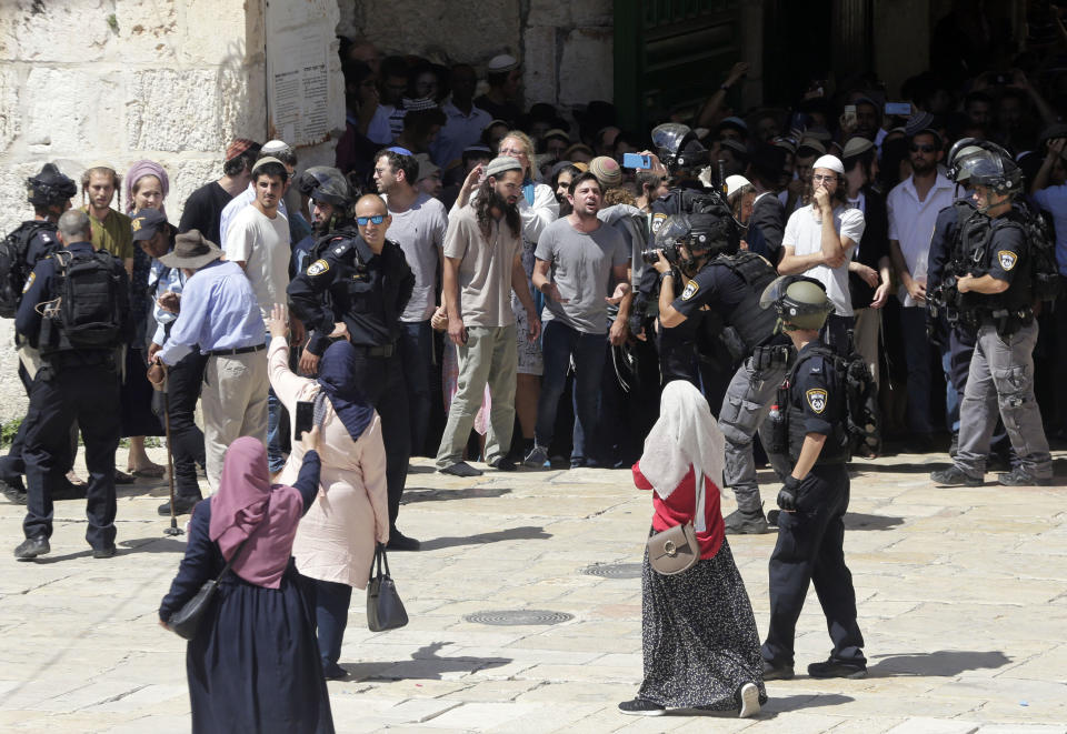 Palestinian women confornt Jewish worshippers as the enter al-Aqsa mosque compound in Jerusalem, Sunday, Aug 11, 2019. Clashes have erupted between Muslim worshippers and Israeli police at a major Jerusalem holy site during prayers marking the Islamic holiday of Eid al-Adha. Tens of thousands of Muslims had flocked to the site in Jerusalem's Old City early Sunday for holiday prayers, police said. Jews are also observing on Sunday the Ninth of Av, a day of fasting and mourning for the destruction of the two Biblical temples which stood at the site in antiquity. (AP Photo/Mahmoud Illean)