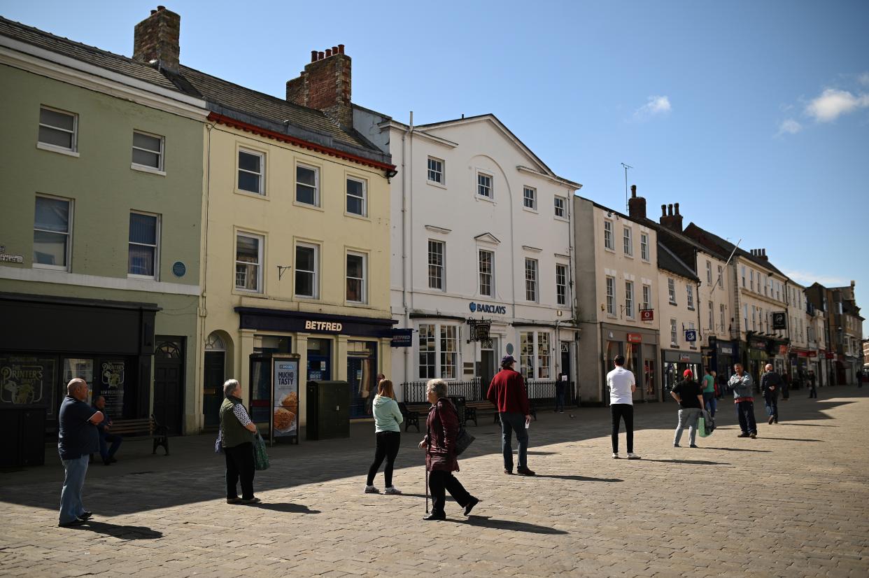 People observe social distancing guidelines, standing two meters (2M) apart, as they queue to enter shops and banks in Pontefract, northern England, on April 27, 2020, as life in Britain continues during the nationwide lockdown to combat the novel coronavirus. - Prime Minister Boris Johnson on Monday made his first public appearance since being hospitalised with coronavirus three weeks ago, saying Britain was beginning to "turn the tide" on the outbreak but rejecting growing calls to ease a nationwide lockdown. (Photo by Oli SCARFF / AFP) (Photo by OLI SCARFF/AFP via Getty Images)