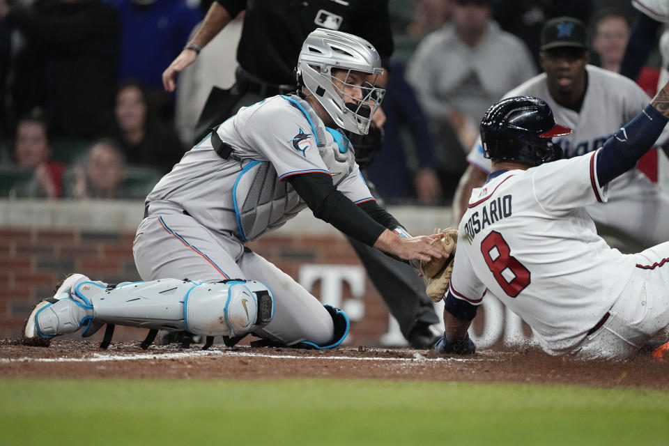 Atlanta Braves Eddie Rosario (8) is tagged out by Miami Marlins catcher Jacob Stallings (58) as he tried to score on a Vaughn Grissom base hit during the sixth inning of a baseball game Wednesday, April 26, 2023, in Atlanta. (AP Photo/John Bazemore)
