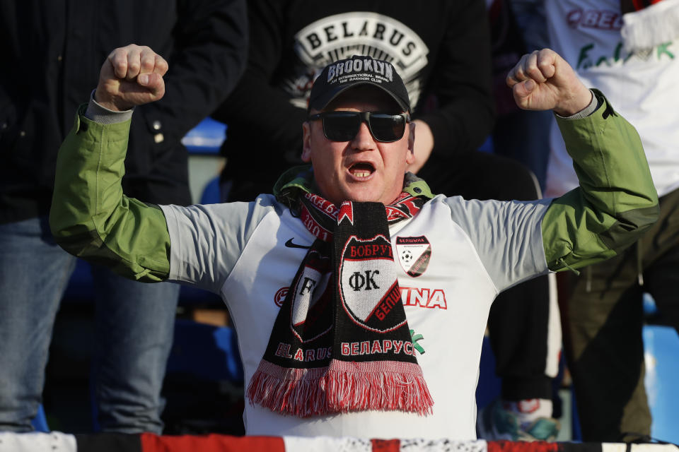 In this photo taken on Friday, March 27, 2020, a fan of Belshina Bobruisk team cheers during the Belarus Championship soccer match between Torpedo-BelAZ Zhodino and Belshina Bobruisk in the town of Zhodino, Belarus. Longtime Belarus President Alexander Lukashenko is proudly keeping soccer and hockey arenas open even though most sports around the world have shut down because of the coronavirus pandemic. The new coronavirus causes mild or moderate symptoms for most people, but for some, especially older adults and people with existing health problems, it can cause more severe illness or death. (AP Photo/Sergei Grits)